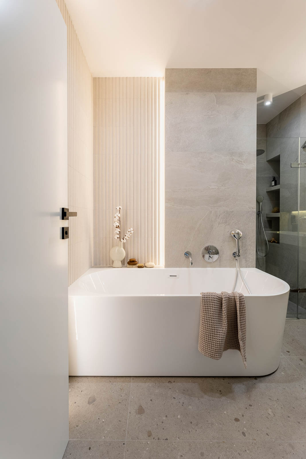 Modern bright bathroom with lamella wall. Big white bath with si